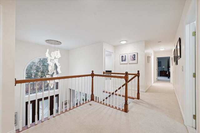 hallway with light colored carpet and a chandelier