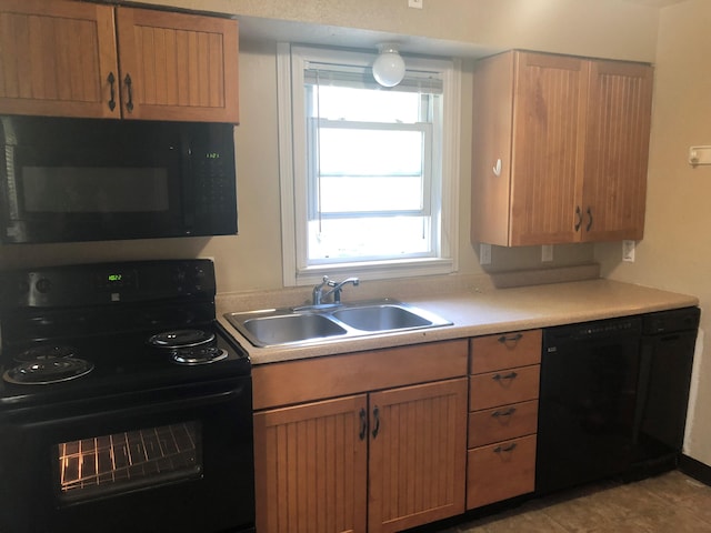 kitchen with black appliances, light tile patterned floors, and sink