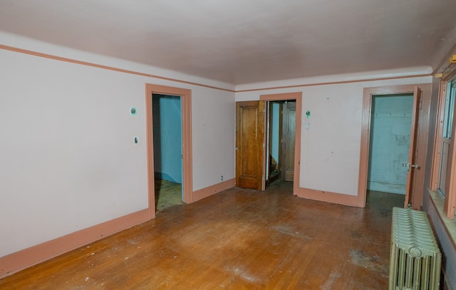 unfurnished room featuring wood-type flooring and radiator heating unit