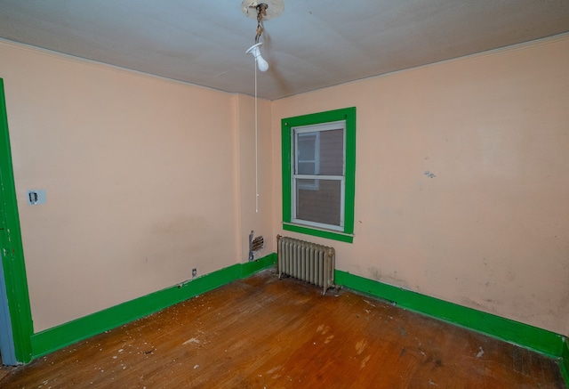 empty room featuring radiator heating unit and hardwood / wood-style flooring