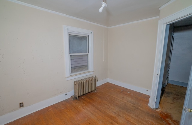 empty room with radiator heating unit, ornamental molding, and hardwood / wood-style flooring