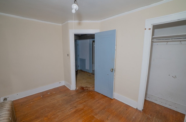 unfurnished bedroom with a closet, ornamental molding, and hardwood / wood-style flooring