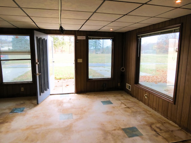 interior space with a drop ceiling and wooden walls