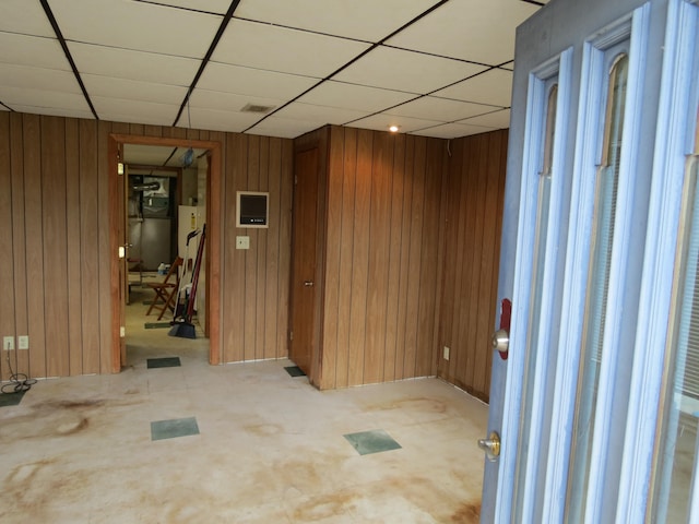 empty room featuring a drop ceiling and wood walls