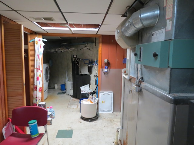 basement featuring a paneled ceiling, heating unit, and washer / clothes dryer