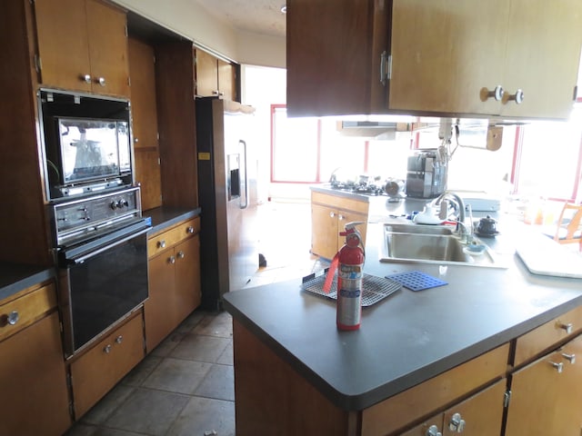 kitchen with sink, black appliances, and dark tile patterned flooring