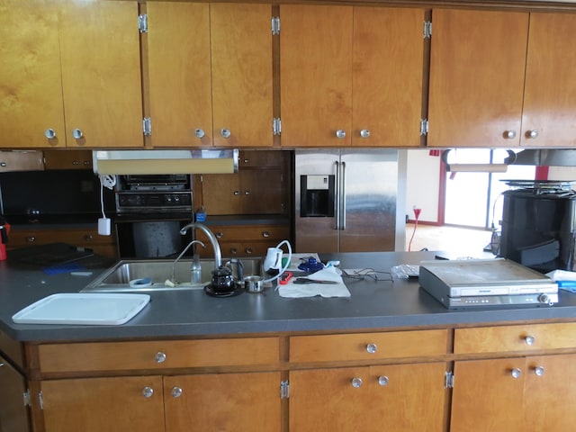 kitchen with stainless steel fridge with ice dispenser, oven, and sink