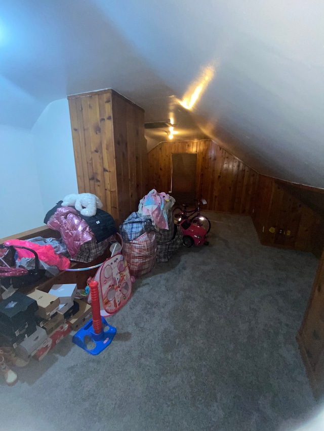 bonus room featuring carpet, vaulted ceiling, ceiling fan, and wood walls