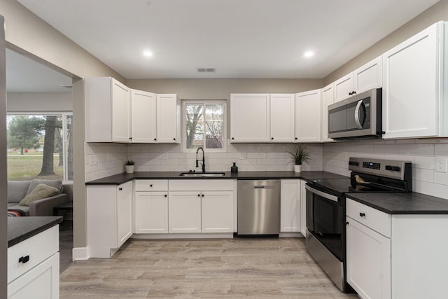 kitchen featuring white cabinets, light wood-type flooring, stainless steel appliances, and sink