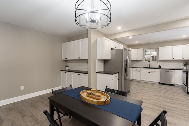 dining room with sink, light hardwood / wood-style floors, and an inviting chandelier