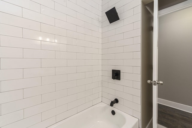 bathroom with hardwood / wood-style floors and tiled shower / bath