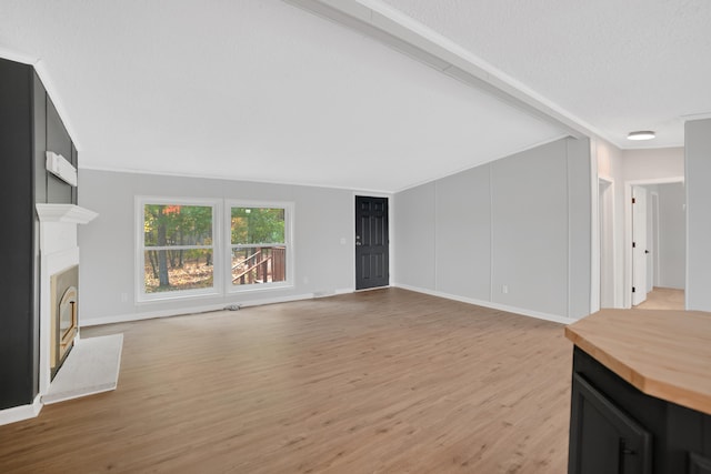 unfurnished living room featuring light wood-type flooring and a textured ceiling