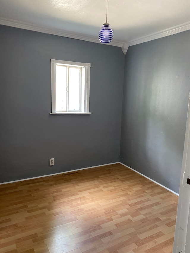 empty room with light wood-type flooring and crown molding