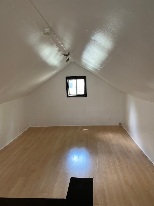 additional living space featuring light hardwood / wood-style floors and lofted ceiling