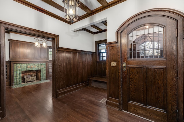 entryway featuring beam ceiling, dark wood-type flooring, a wealth of natural light, and a chandelier