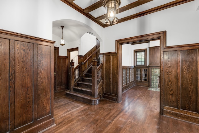 foyer entrance with crown molding, beamed ceiling, and dark wood-type flooring