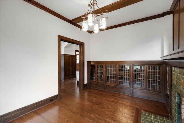 empty room featuring crown molding, dark wood-type flooring, and a notable chandelier