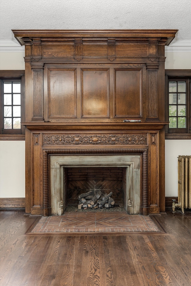 room details with radiator heating unit, crown molding, wood-type flooring, and a textured ceiling