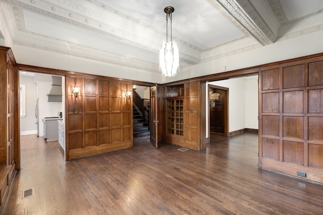 empty room with a raised ceiling, dark hardwood / wood-style flooring, and ornamental molding