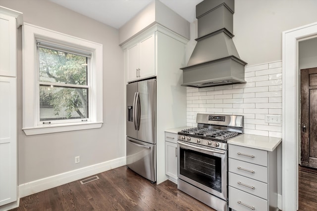 kitchen with tasteful backsplash, dark hardwood / wood-style flooring, appliances with stainless steel finishes, white cabinets, and custom exhaust hood