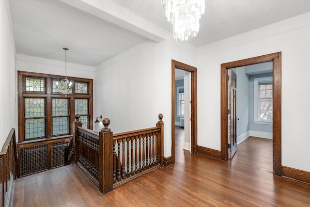 corridor featuring dark wood-type flooring and an inviting chandelier