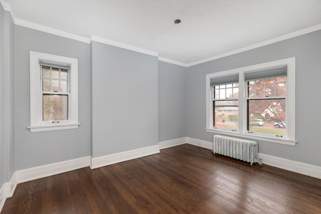 spare room with ornamental molding, dark wood-type flooring, radiator, and a healthy amount of sunlight