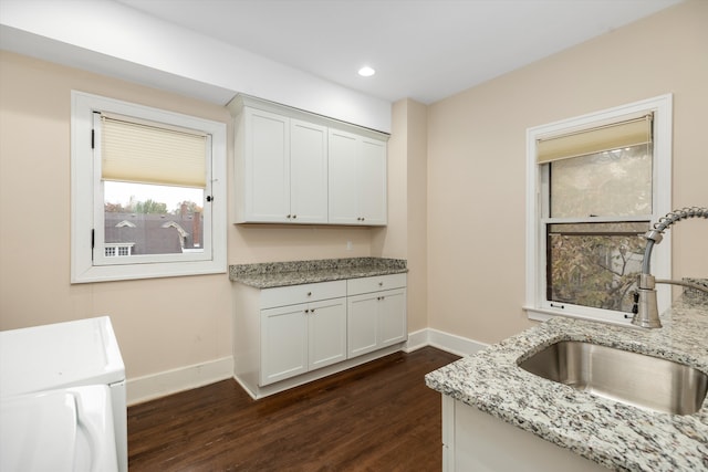 kitchen with light stone countertops, dark hardwood / wood-style flooring, white cabinetry, and sink