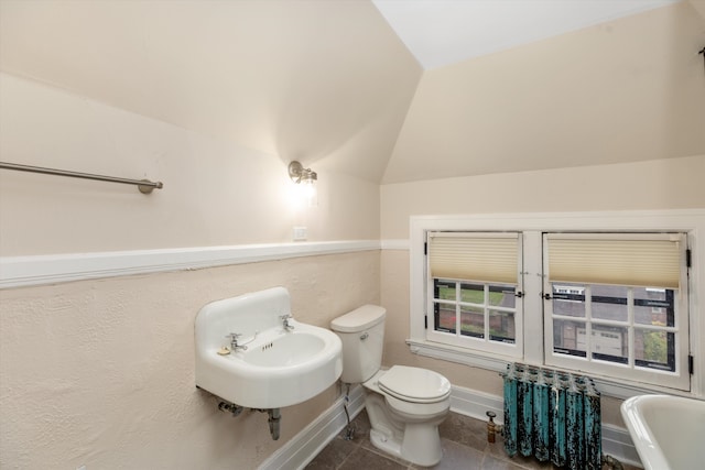 bathroom featuring toilet, tile patterned flooring, lofted ceiling, and sink