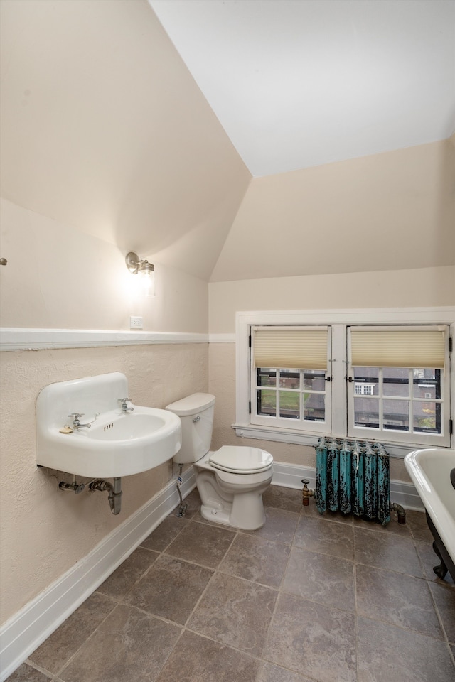 bathroom with lofted ceiling, tile patterned floors, sink, toilet, and a tub