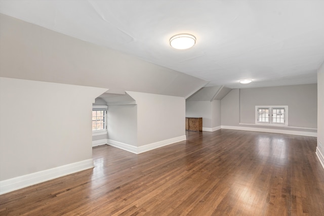 additional living space featuring plenty of natural light, dark wood-type flooring, and vaulted ceiling