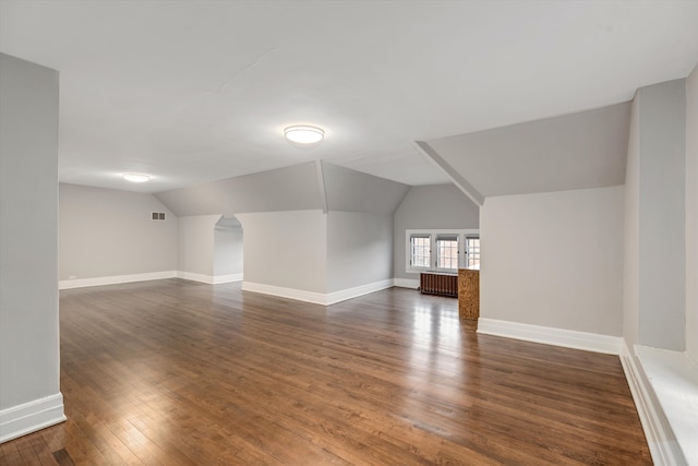 bonus room featuring dark hardwood / wood-style floors, radiator, and vaulted ceiling