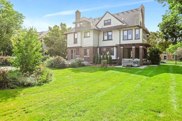 back of property featuring a yard and a hot tub