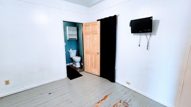 bedroom featuring connected bathroom and light wood-type flooring