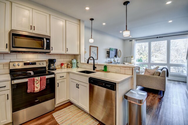 208 Gillis St, Traverse City, MI 49684 - kitchen with stainless steel appliances, a sink, a peninsula, open floor plan, and backsplash