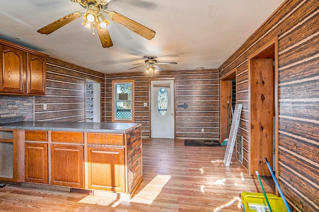 kitchen featuring tasteful backsplash, wooden walls, light hardwood / wood-style flooring, and ceiling fan