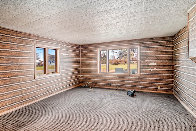 carpeted spare room featuring wooden walls