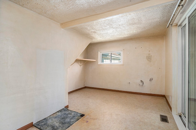 additional living space featuring a textured ceiling and vaulted ceiling