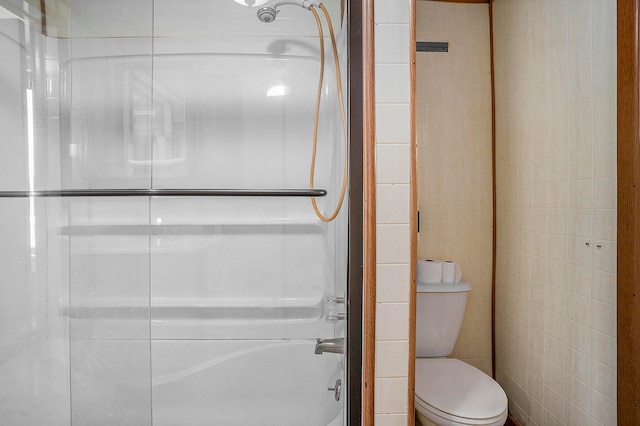 bathroom featuring toilet, shower / tub combination, and tile walls