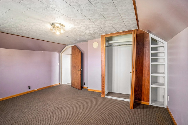 bonus room with built in shelves, dark carpet, and lofted ceiling