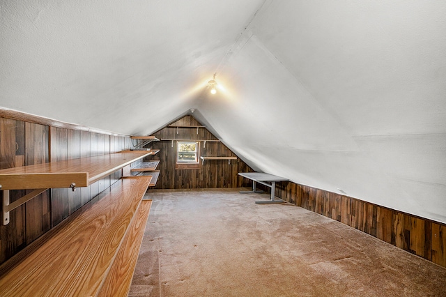 additional living space with carpet flooring, wooden walls, and vaulted ceiling