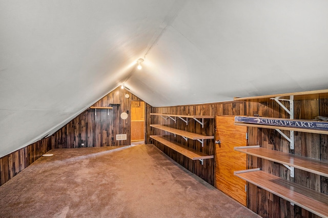 interior space featuring wooden walls, carpet, and vaulted ceiling