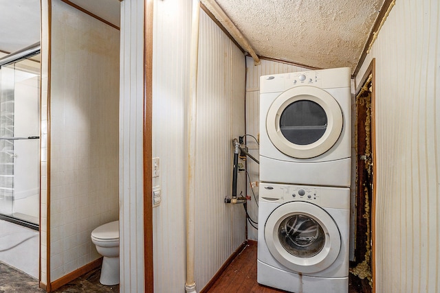 clothes washing area with dark hardwood / wood-style floors, a textured ceiling, and stacked washer and clothes dryer