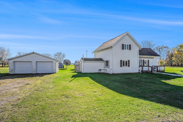 back of house featuring a yard, an outdoor structure, and a garage