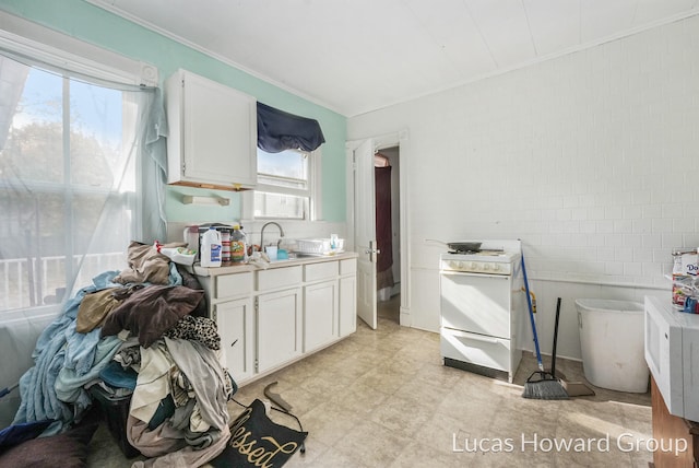 kitchen featuring tile walls, white cabinetry, sink, and gas range gas stove