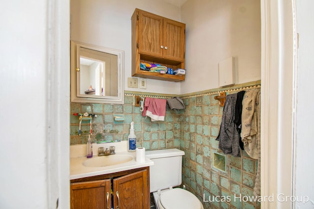 bathroom with vanity, toilet, and tile walls