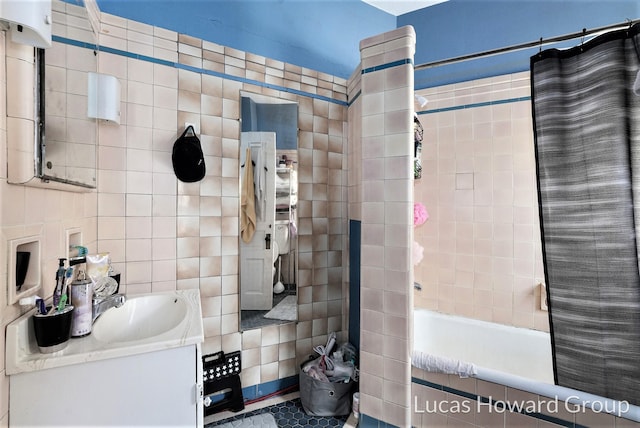 bathroom with tile patterned floors, shower / tub combo with curtain, vanity, and tile walls