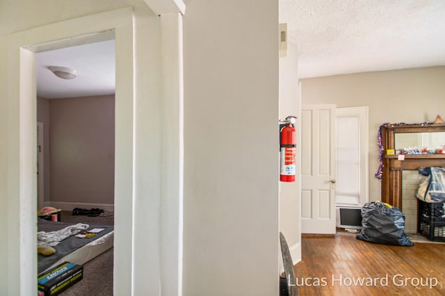 hall featuring wood-type flooring and a textured ceiling