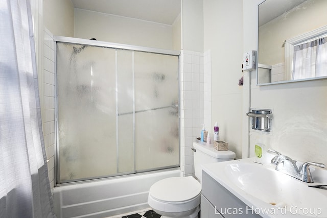 full bathroom featuring combined bath / shower with glass door, vanity, and toilet