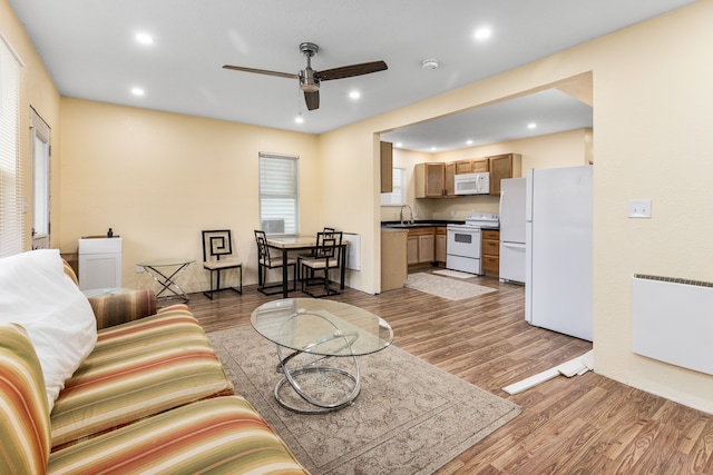 living room with radiator heating unit, light hardwood / wood-style floors, ceiling fan, and sink