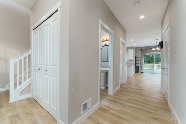 hall featuring light wood-type flooring and a chandelier